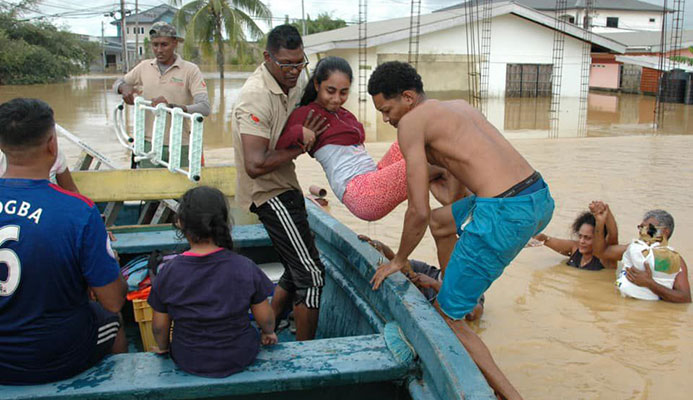 Ravi Kalpoo, centre, of Klapoo Tours is assisted by a villager during efforts to help marooned flood victims in central Trinidad.  -Photo: Courtesy Kalpoo Tours