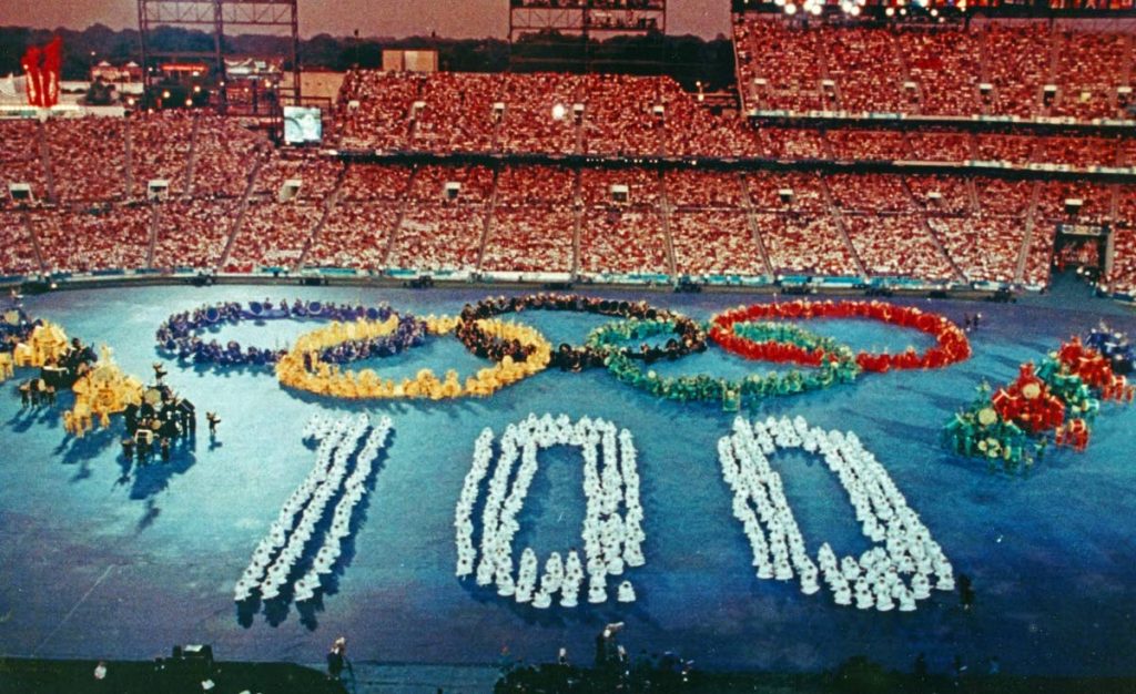 Call to Nations, the first segment of the 1996 Atlanta Olympic games opening ceremony, designed by Peter Minshall. The performers formed the Olympic rings and the number 100 to represent 100 years since the founding of the modern Olympics in 1896. Photo courtesy Don Mischer, producer of the ceremonies. - Call to Nations, the first segment of the 1996 Atlanta Olympic games opening ceremony, designed by Peter Minshall. The performers formed the Olympic rings and the number 100 to represent 100 years since the founding of the modern Olympics in 1896. Photo courtesy Don Mischer, producer of the ceremonies. -