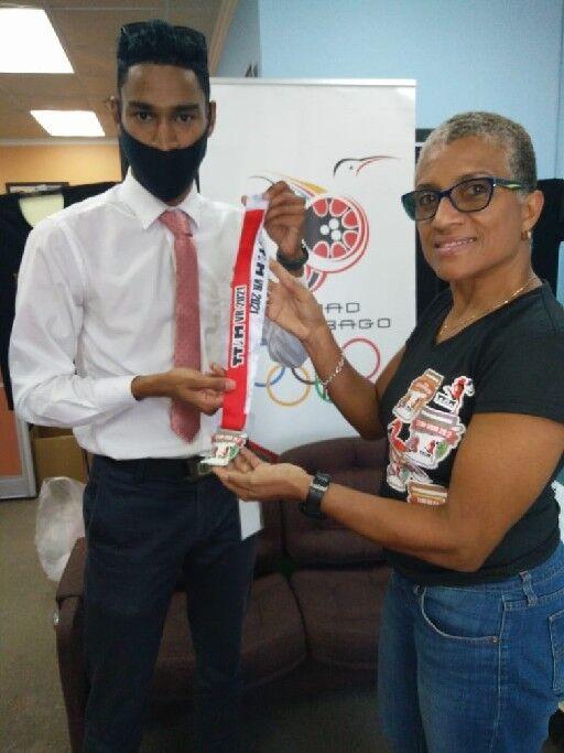 TOP TIME: Corey Joseph-Samaroo, left, receives his virtual Trinidad and Tobago International Marathon (TTIM) medal from TTIM chairperson Diane Henderson, at the T&T Olympic Committee (TTOC) office, Abercromby Street, Port of Spain, on Thursday. Joseph-Samaroo recorded the fastest time in the event, the One-A-Week runner completing 26.2 miles in three hours, 17 minutes and 38 seconds. TOP TIME: Corey Joseph-Samaroo, left, receives his virtual Trinidad and Tobago International Marathon (TTIM) medal from TTIM chairperson Diane Henderson, at the T&T Olympic Committee (TTOC) office, Abercromby Street, Port of Spain, on Thursday. Joseph-Samaroo recorded the fastest time in the event, the One-A-Week runner completing 26.2 miles in three hours, 17 minutes and 38 seconds.