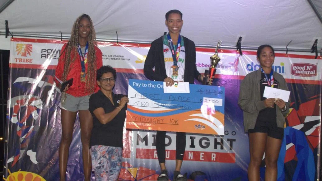 WOMEN’S WINNER: Alexia John collects her winner’s cheque after topping the women’s category in the Midnight 10k event, early Sunday morning at the Queen’s Park Savannah. April Francis, left, placed second while Zara Suite-Stewart finished third.  —Photo courtesy BAFA Sports (Image obtained at trinidadexpress.com)